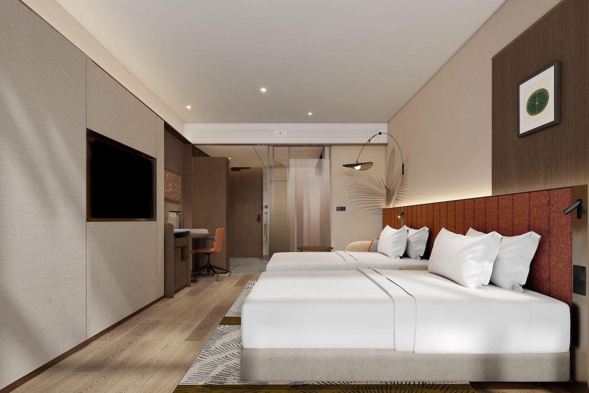 Una habitación de hotel moderna con una cama grande, un escritorio y zona de ducha.
