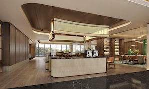 A modern hotel lobby with a central island, wooden paneling, and a mezzanine level.