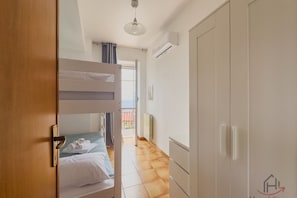 Una habitación de hotel con literas, un armario, un radiador y vistas al exterior.