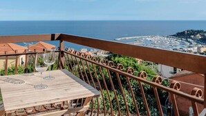 Un balcon avec une table et deux verres à vin, donnant sur une ville côtière.
