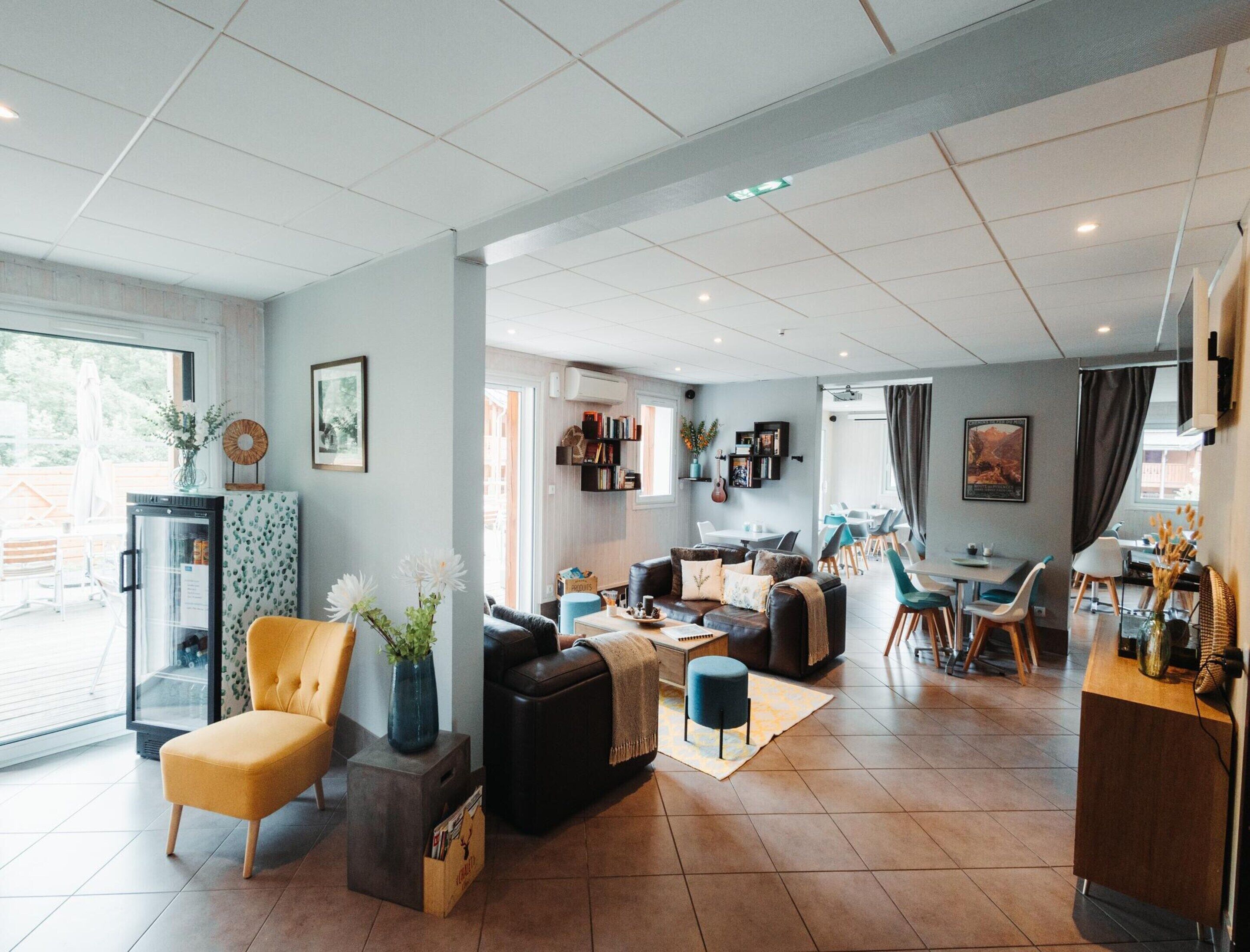 A modern living room with a sofa, armchair, and coffee table. There is a dining area with a table and chairs.