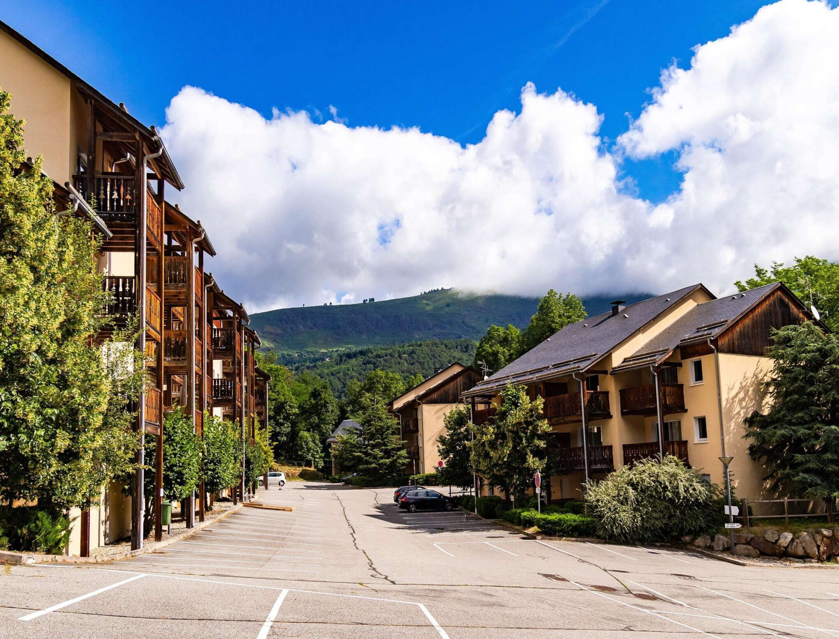 A parking lot with buildings on either side, a mountain in the background, and a clear sky.