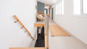 Eine Treppe mit einer Holzhandläufe, einem Korbstuhl und einer gewebten Matte auf dem Boden.