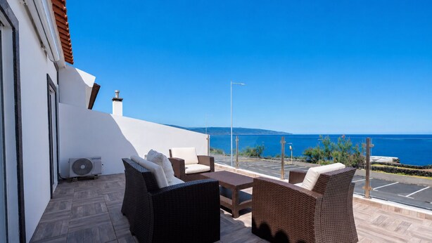 Eine Terrasse mit Korbmöbeln, einer Klimaanlage und Meerblick.