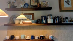 Una cocina con estantes que exhiben diverso menaje, una lámpara colgante y obras de arte enmarcadas.