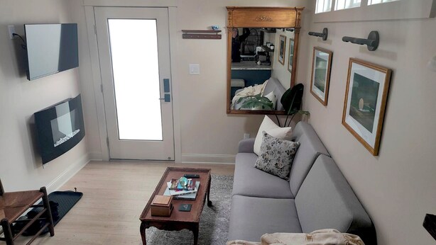 Una sala de estar con sofá, mesa de centro, televisor y una puerta con letrero de 'No Fumar'.