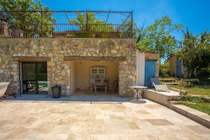 Un bâtiment en pierre doté d’un patio, d’un espace extérieur aménagé avec des sièges et d’un espace piscine.