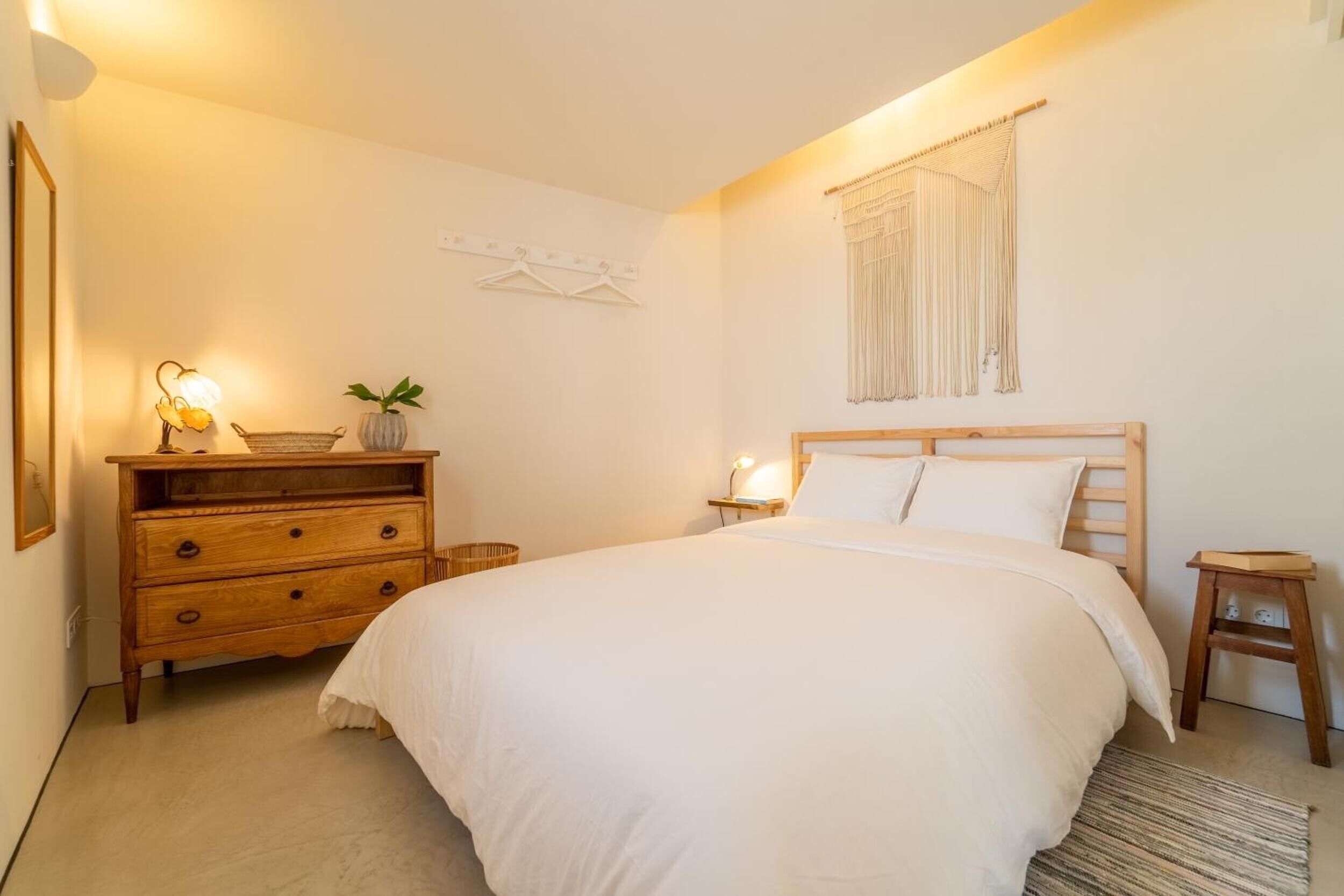 Un dormitorio con cama, cómoda, mesita de noche, lámpara y decoración en la pared.