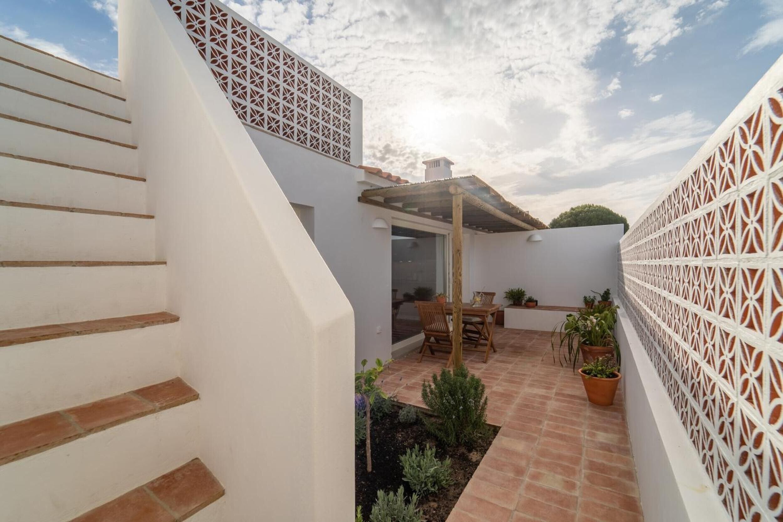 Un edificio blanco con un patio, escalones y un celosía decorativa blanca.