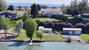 A lakeside property with multiple buildings, a dock, and a grassy area with trees.