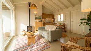 A cozy living room with a sofa, a small wooden table, and a colorful rug. - Casinha do Burro – Casas do Poente: Cozy Cottage with Private Patio (Rogil)
