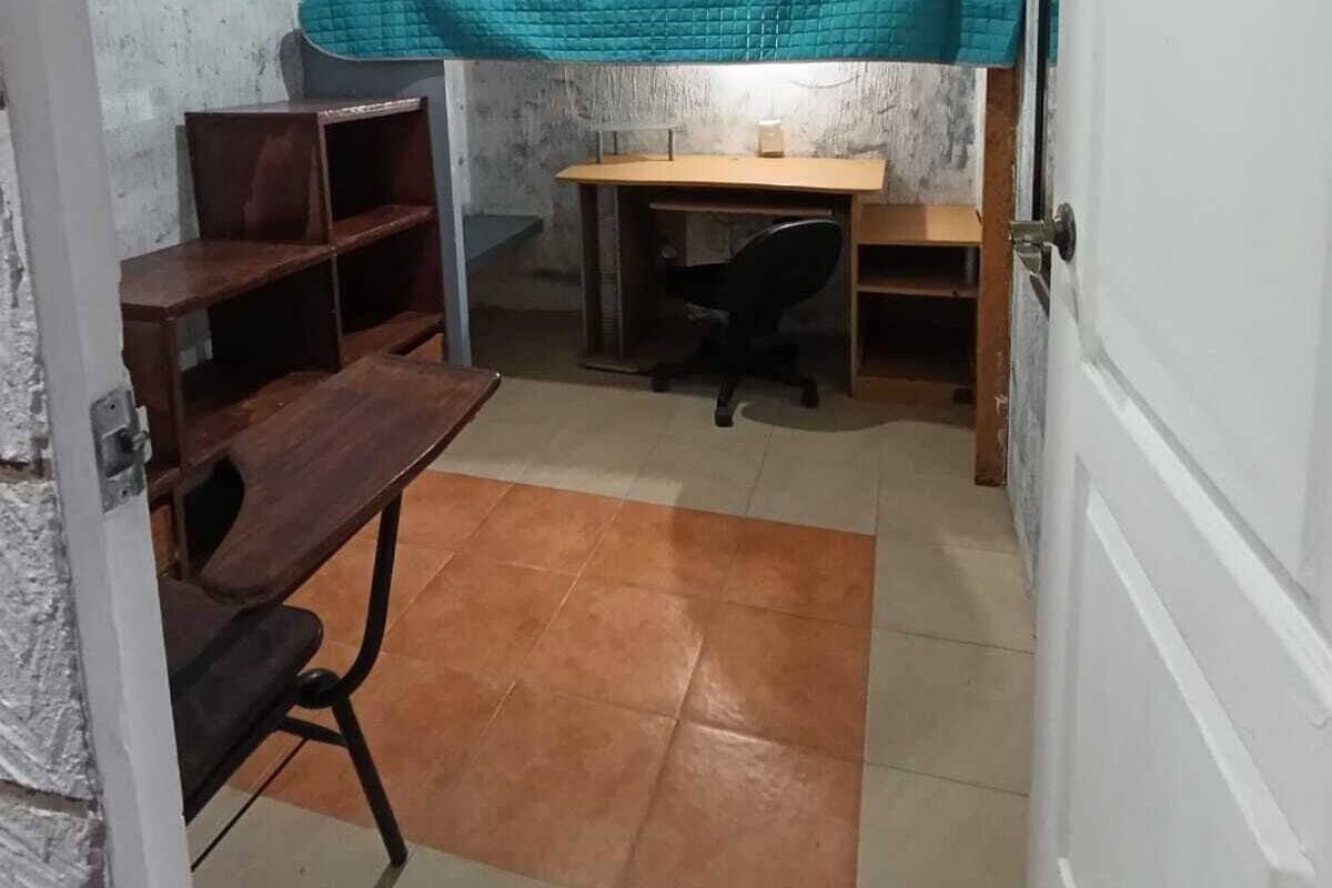 Ein kleines Zimmer mit Etagenbett, Schreibtisch, Stuhl und kleinem Regal.