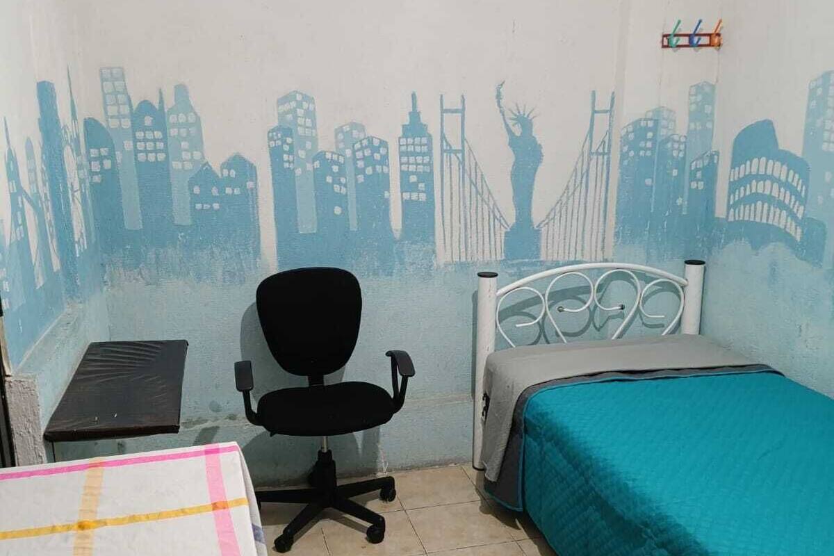 Ein Zimmer mit Bett, Schreibtisch, Stuhl und Wandgemälde.