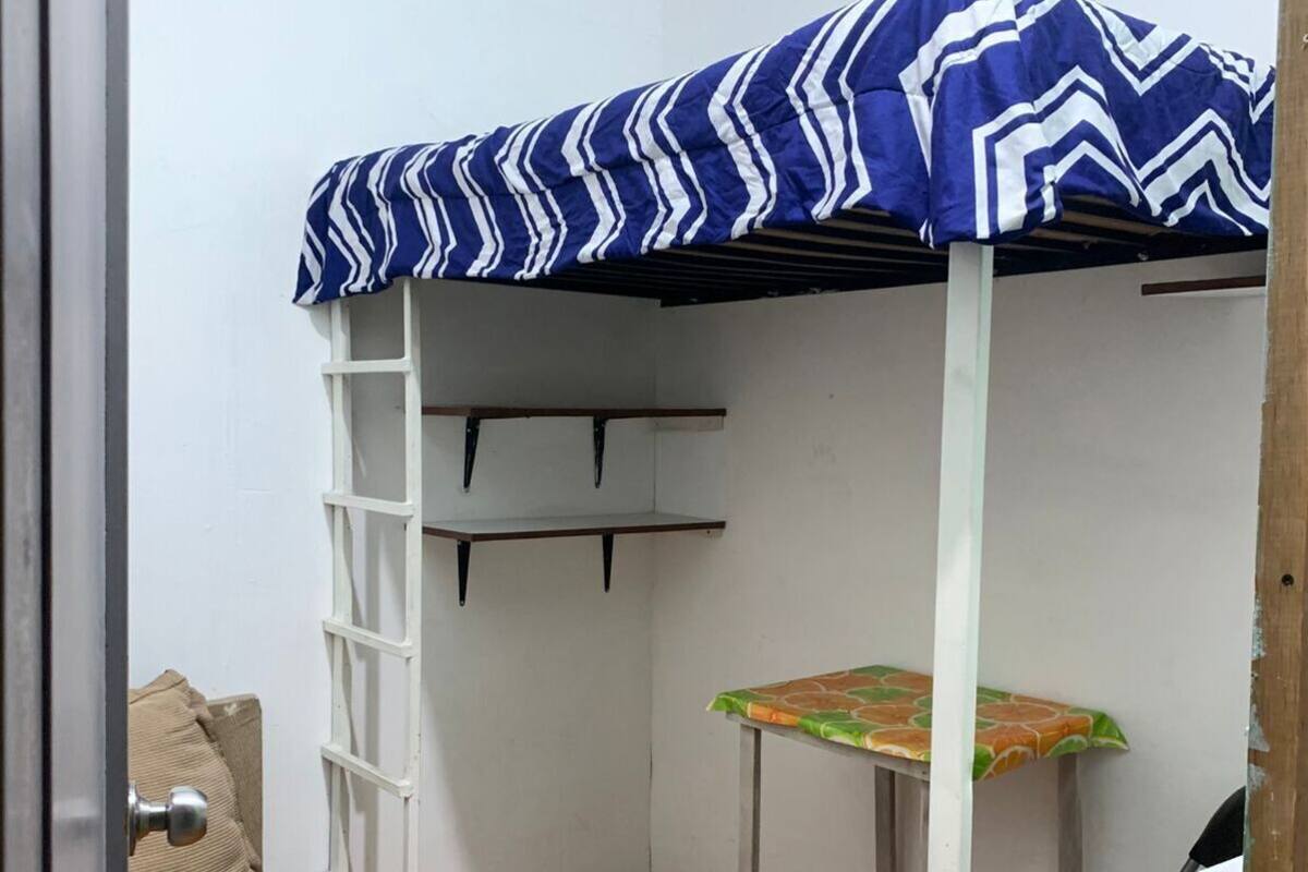 Ein kleines Zimmer mit einem Etagenbett, einem kleinen Tisch, einem Stuhl und einer Treppe.