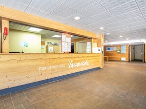 A reception desk with 'Bienvenue Chez Vacancesole' signage, a wooden interior, and a tiled floor. - Stay Near Galibier Pass (Valloire)