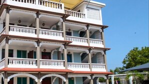 Un edificio de varios pisos con balcones, un acceso cubierto y un patio empedrado.