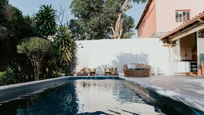 A swimming pool with a white wall and trees in the background. - Cozy House with Gourmet Area and Pool (Vila Velha)