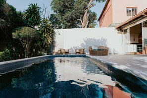 A swimming pool with a white wall and trees in the background. - Cozy House with Gourmet Area and Pool (Vila Velha)