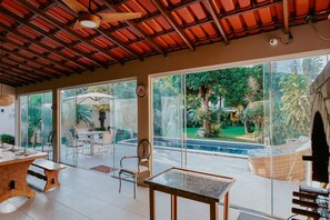 A spacious indoor area with a large glass door leading to a pool, a dining table, and chairs. - Cozy House with Gourmet Area and Pool (Vila Velha)