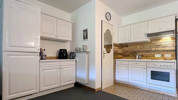 A compact kitchen with white cabinetry, a built-in oven, and a wooden backsplash.