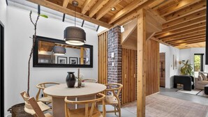 A dining area with a round table, wooden chairs, a vase, and a hanging light fixture. - Stylish 2BR/2BA |Large Private Patio|Near Downtown (Vancouver)