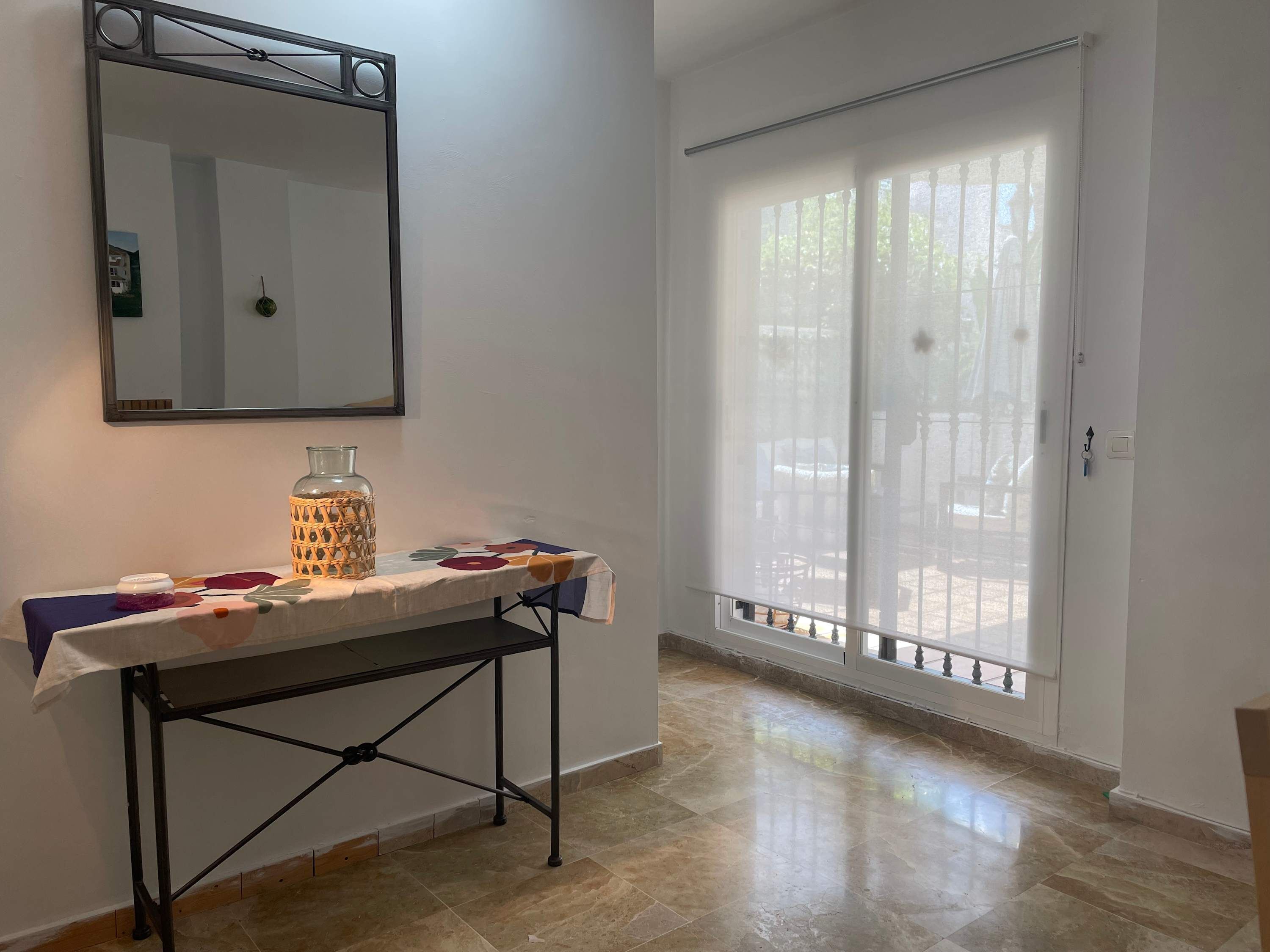 A room with a table, a mirror, a window with a view, and a door.
