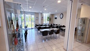 A spacious room with multiple tables and chairs, a glass display case with bottles, and a clock on the wall. - Heritage Apartment for 4 in Epernay (Epernay)