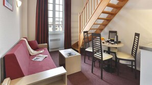 A room with a red sofa, a small table, two chairs, a wooden staircase, and a window with curtains. - Heritage Apartment for 4 in Epernay (Epernay)