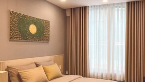 Un dormitorio con cama, cortinas y un cuadro en la pared.