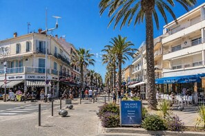 A bustling street with shops, outdoor seating, palm trees, and a sign welcoming visitors. - Blanche de Castille, near the sea and city center (Palavas-les-Flots)