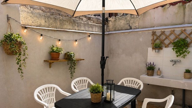 Un patio con una mesa, sillas, luces colgantes, plantas en macetas y un lavamanos.