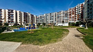 Een wooncomplex met meerdere appartementen, een speeltuin en een verhard pad.