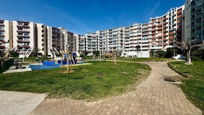 A residential building complex with multiple apartment buildings, a playground, and a paved pathway. - Le Port Carnon, Parenthèse Marine (Carnon-Plage)