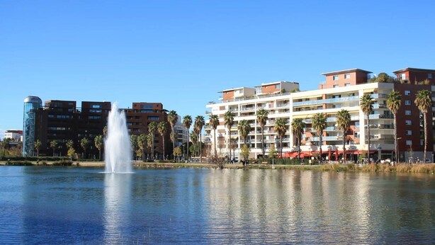 A waterfront hotel with a fountain, palm trees, and modern buildings in the background. - L'apogée, centre et terrasse (Montpellier)