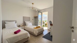 A hotel room with two beds, a small desk, a wardrobe, and a sliding glass door leading to a balcony. - L'apogée, centre et terrasse (Montpellier)