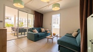 A modern living room with a sofa set, a coffee table, and a view through a glass door to an outdoor area. - L'apogée, centre et terrasse (Montpellier)