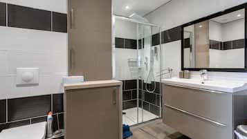 Une salle de bain moderne avec une douche à parois de verre, un lavabo avec un miroir et des toilettes.