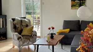 Een moderne woonkamer met een bank, een stoel, een salontafel en een groot raam.