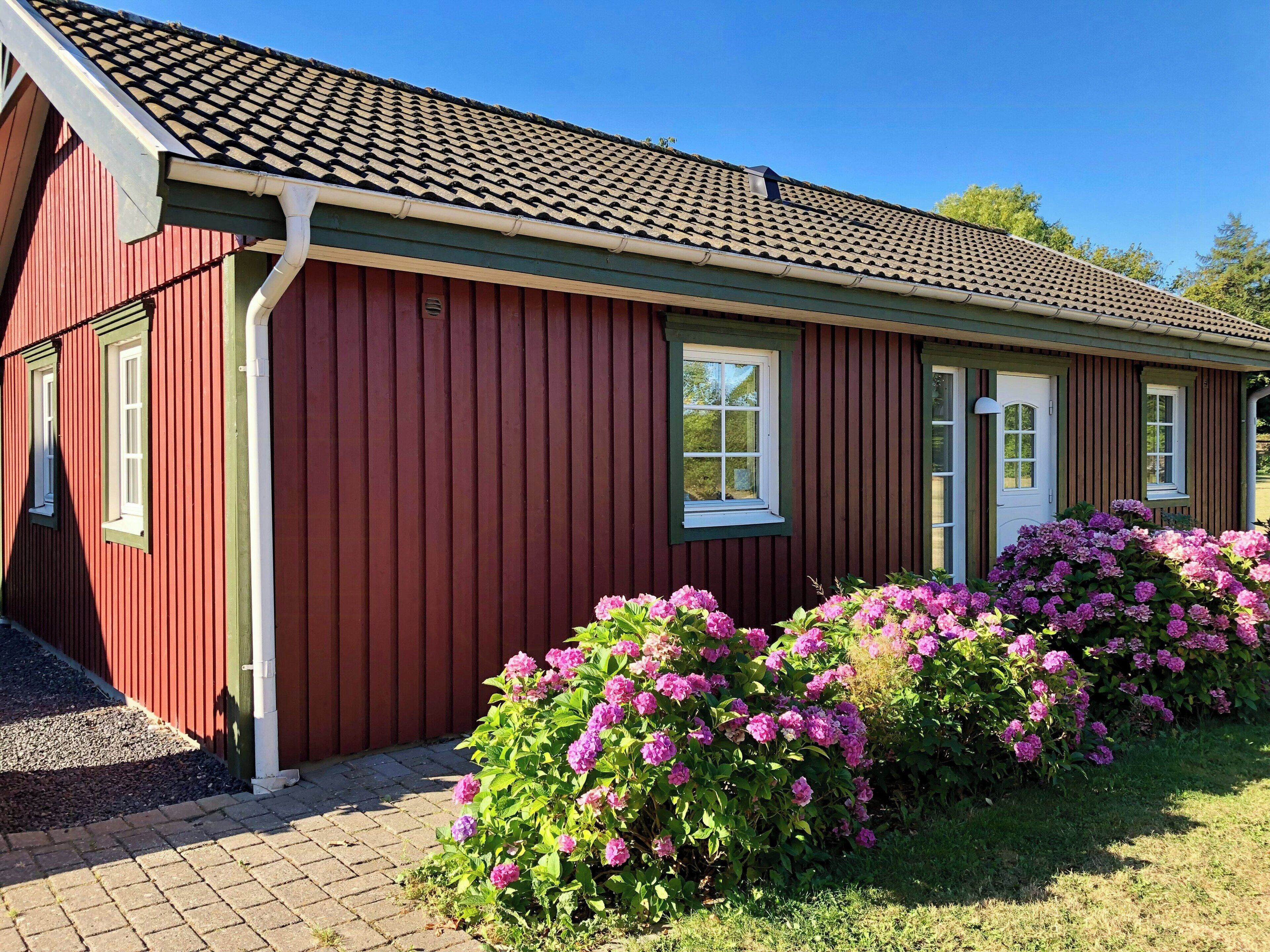 A red wooden building with a tiled roof, a white door, and windows.