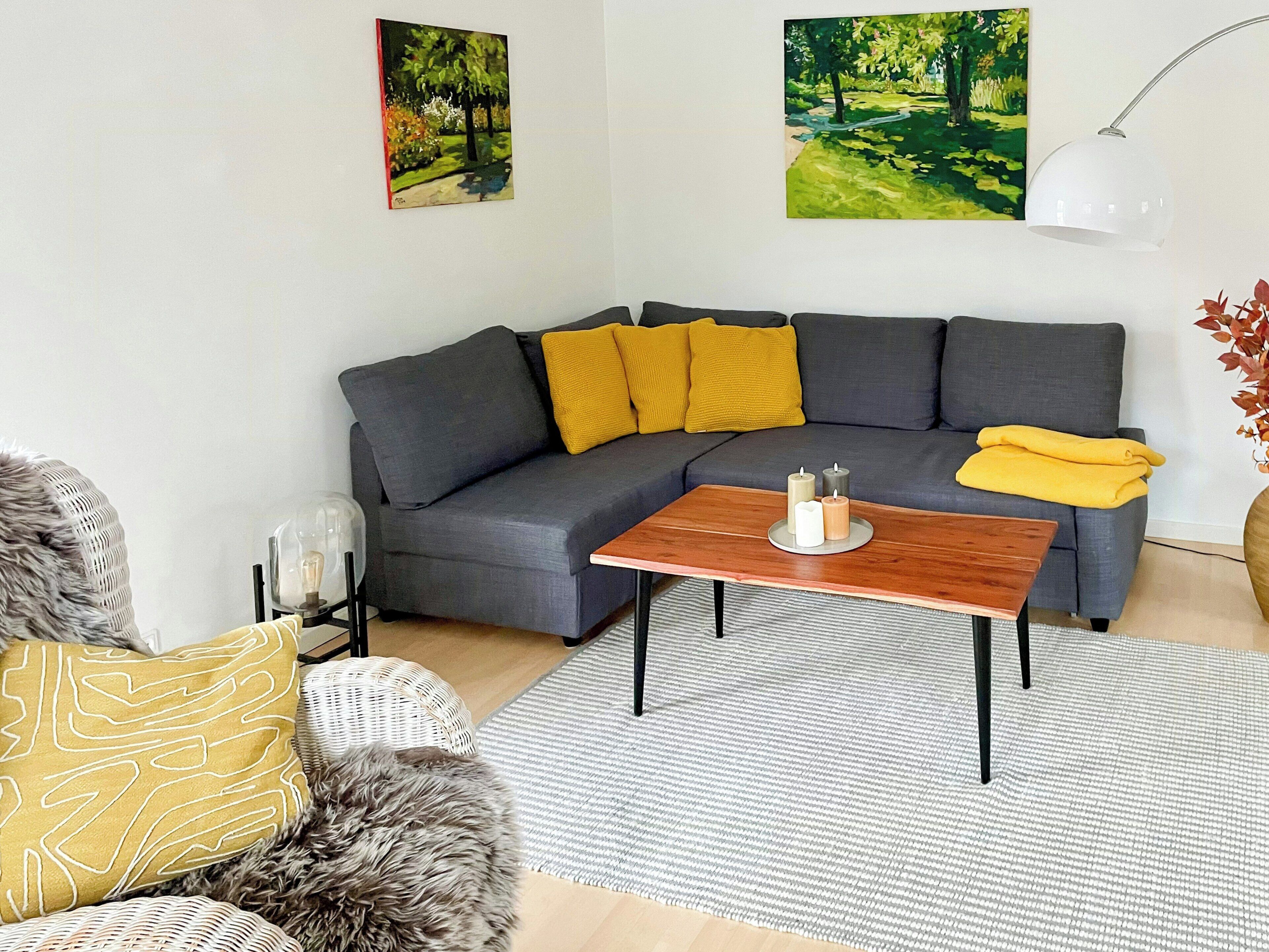 En moderne stue med en grå sofa, et træbord og en grå måtte.