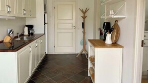 Een keuken met witte kastjes, een houten aanrecht, een koffieapparaat en een deur met decoratie.