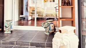 A modern interior with a glass door leading to a bedroom, a wooden shelf with decorative items, and a hanging light fixture. - The Elephant House in Vivonne (Vivonne)