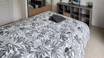 A bedroom with a bed, a wardrobe, a mirror, and a shelf with decorative items.