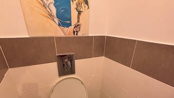 Een badkamer met een toilet, een bidet en een toiletrolhouder aan de muur.