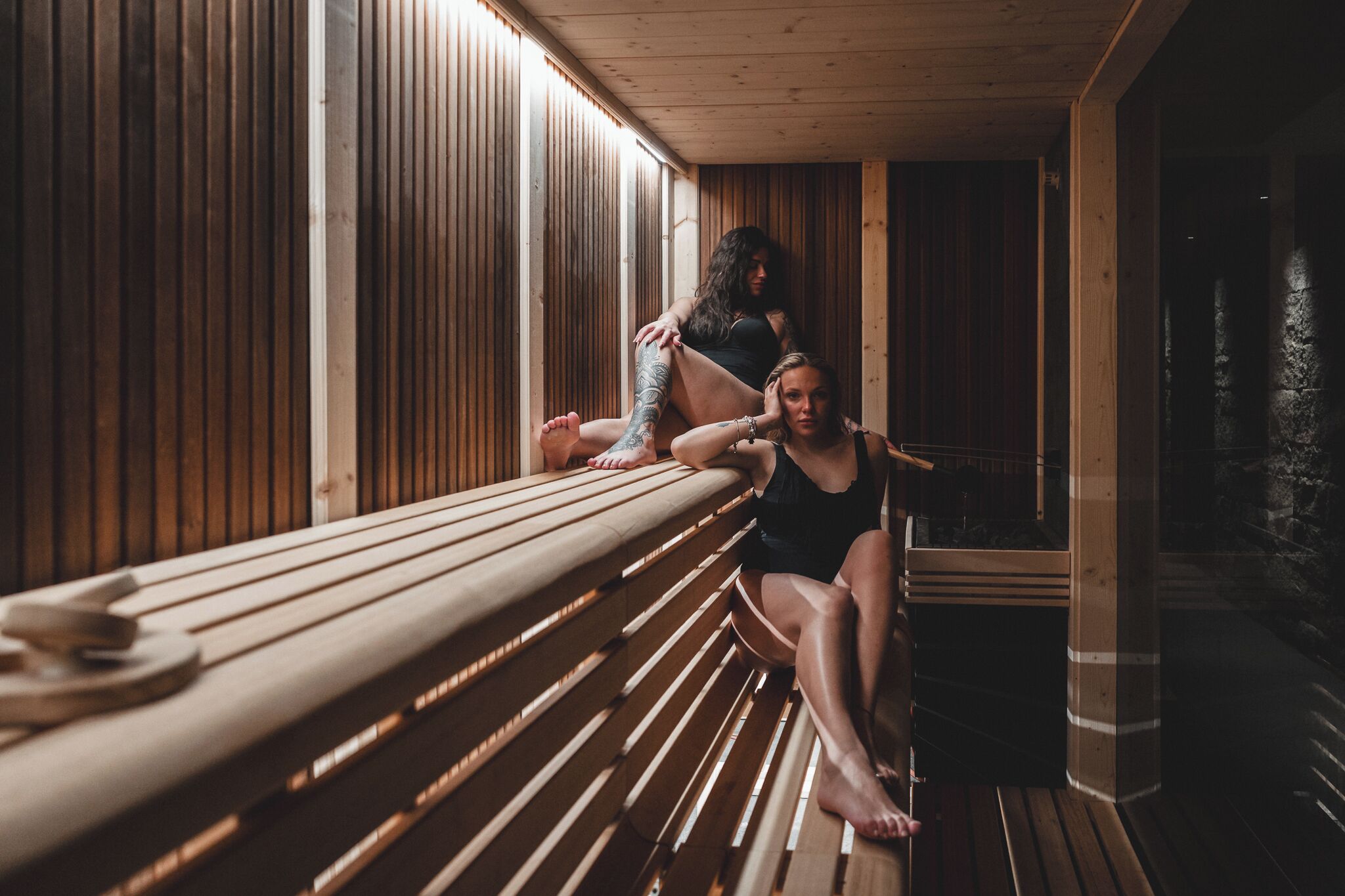A sauna with wooden benches and a person sitting on one.