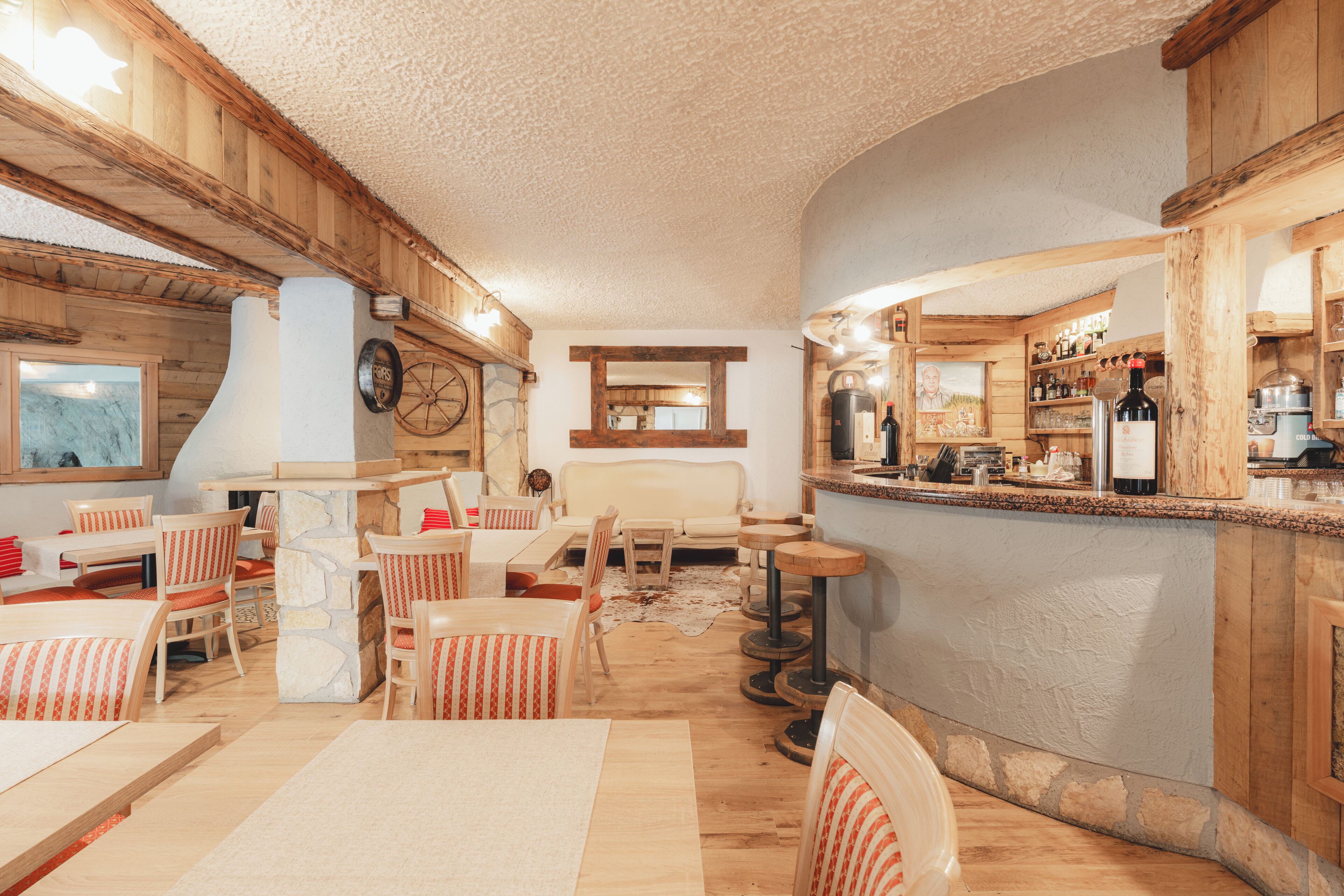 Ein gemütliches Restaurant mit Holzwänden, einem Steinofen und einer Bar.