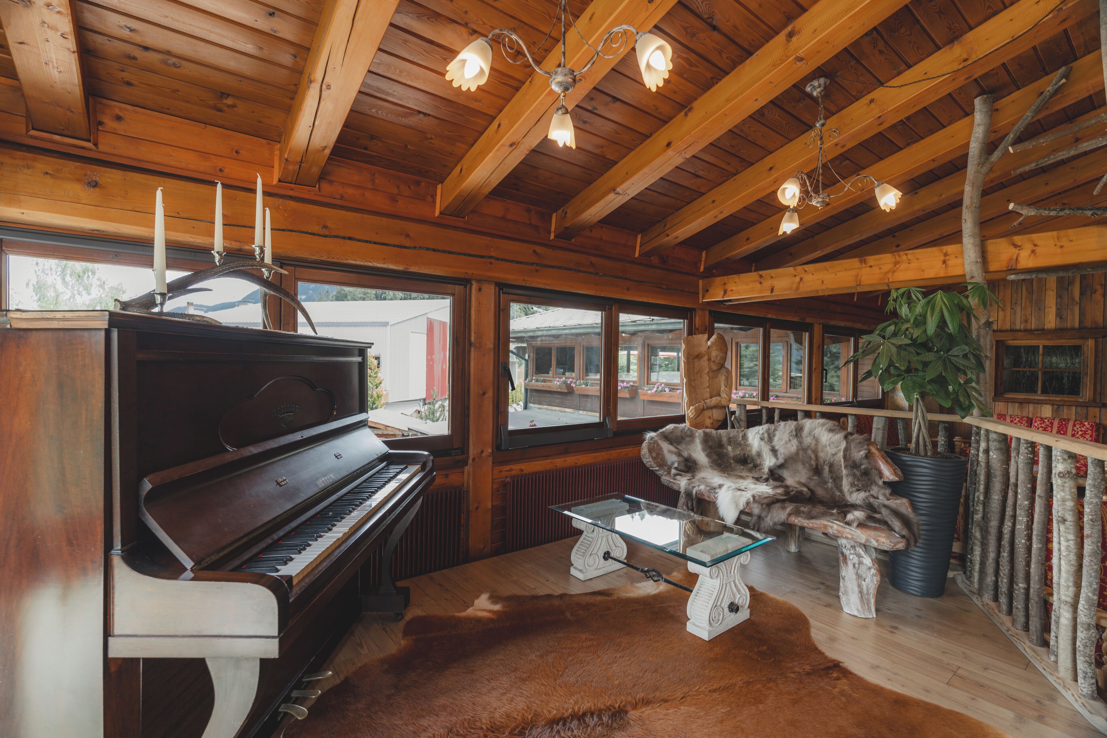 A wooden interior with a grand piano, a glass coffee table, and a rustic bench.