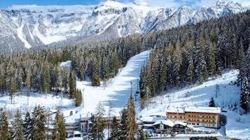 A snow-covered mountain resort with a ski slope, lodge, and forested area.