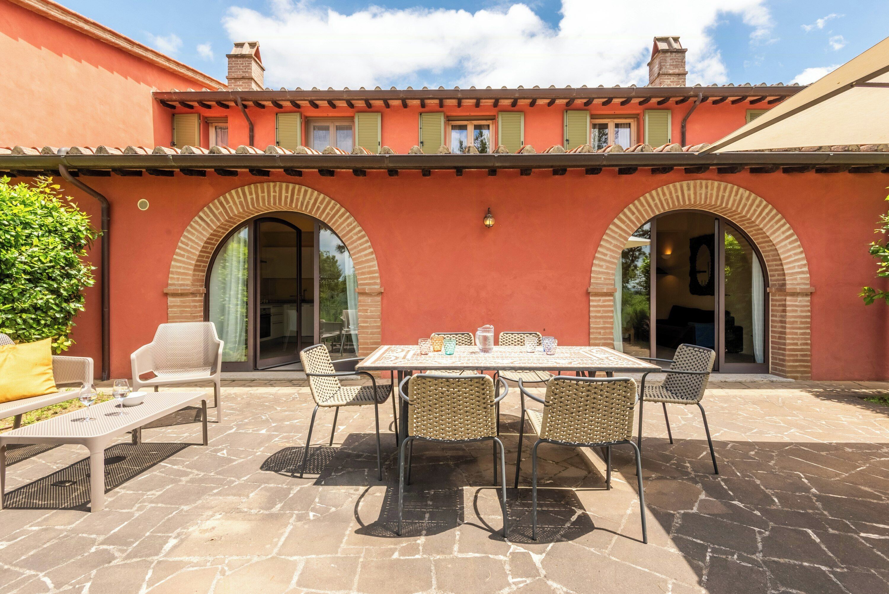 An outdoor patio with a table and chairs, a bench, and a brick wall.