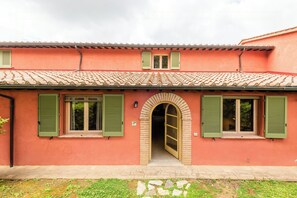 Ein Gebäude mit einem Ziegeldach, grünen Fensterläden und einem zentralen Rundbogenportal.